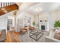 Bright living room with hardwood floors, fireplace, and an open layout leading to the dining area at 2350 N Ogden St, Denver, CO 80205