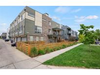 Modern townhome features a mix of brick and siding, a fenced front yard, and a second-story balcony at 1921 Hooker St, Denver, CO 80204