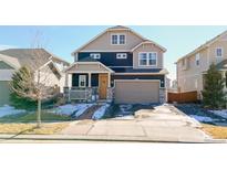 Two-story home with a blend of dark siding and light stone accents, complemented by a well-manicured lawn and a two-car garage at 17548 E 103Rd Dr, Commerce City, CO 80022