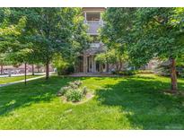 Charming home featuring a stone facade, a manicured lawn, and mature trees at 8427 S Hoyt Way # 107, Littleton, CO 80128