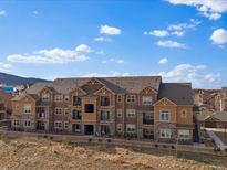 Low-angle shot shows an apartment building with a blue sky, brown siding, and decorative stonework at 9962 W Victoria Pl # 106, Littleton, CO 80127