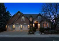 Charming home featuring a three-car garage, stone accents, and a manicured front yard, lit at dusk at 7420 S Wolff St, Littleton, CO 80128