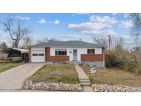 Charming ranch-style home with a brick facade, attached garage, and mature trees under a bright blue sky at 12023 W Virginia Ave, Lakewood, CO 80228