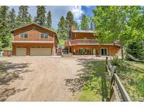 Inviting cabin-style home featuring wood siding, a spacious deck, and an attached two-car garage with large driveway at 11182 S Barney Gulch Rd, Conifer, CO 80433