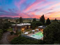 Stunning twilight aerial view of home with a pool and mountain views in the background at 3675 S Perry Park Rd, Sedalia, CO 80135