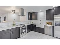 Modern kitchen with black cabinets, white subway tile backsplash, and stainless steel appliances at 6052 Taft St, Arvada, CO 80004