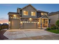 Beautiful home with a stone and siding exterior, three-car garage, and a welcoming front porch at 16595 E 110Th Ave, Commerce City, CO 80022