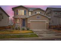 Two-story home with a two-car garage, stone accents, blue shutters, and a well-manicured front yard at 17859 E 108Th Pl, Commerce City, CO 80022
