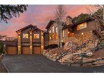 Beautiful home exterior featuring stone accents, a three-car garage, and a well-maintained driveway at 127 Granite Way, Evergreen, CO 80439