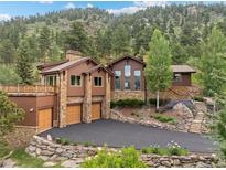 Beautiful exterior featuring a stone-and-siding design, manicured landscaping, and an expansive driveway with mountain backdrop at 127 Granite Way, Evergreen, CO 80439
