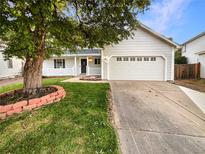 Charming home featuring a white facade, mature tree, and a two-car garage at 14822 E Adriatic Pl, Aurora, CO 80014