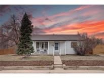 Charming home featuring a cozy front porch and beautiful landscaping under a vibrant sunset sky at 5191 S Logan St, Littleton, CO 80121