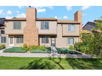 Inviting townhome exterior with brick chimney, manicured lawn and well-maintained landscaping at 892 Summer Dr # 15B, Highlands Ranch, CO 80126