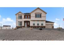 Two-story stucco home with brick accents, manicured gravel landscaping, and attached two car garage at 16197 Paris Way, Brighton, CO 80602