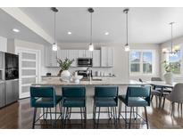 Bright kitchen featuring a large island with seating, pendant lighting, and stainless steel appliances at 16197 Paris Way, Brighton, CO 80602