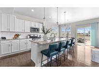 Bright kitchen features white cabinets, granite countertops, stainless appliances and breakfast bar with seating at 16197 Paris Way, Brighton, CO 80602