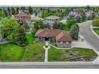 Beautifully landscaped gray house with a well-manicured lawn and other homes in the background at 7170 Windwood Way, Parker, CO 80134