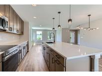 Modern kitchen features stainless appliances, quartz counters, dark cabinets, and island with pendant lighting at 3420 N Steele St, Denver, CO 80205
