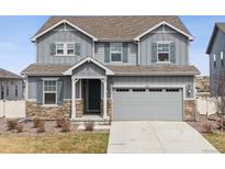 Charming two-story home features a two-car garage, gray siding, stone accents, and matching gray shutters at 6243 Saddle Bow Ave, Parker, CO 80134