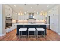 Bright kitchen with white cabinets, stainless steel appliances, and a large island with seating at 775 Woodgate Dr, Highlands Ranch, CO 80126