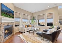 Comfortable living room featuring a brick fireplace, large windows, and stylish furniture at 9581 Firenze Way, Highlands Ranch, CO 80126