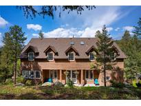 Charming two-story home featuring a welcoming front porch with hanging flower baskets and a beautiful natural setting at 4978 Camel Heights Rd, Evergreen, CO 80439
