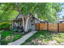 Charming home with gray stone facade, manicured front yard, mature trees, and a modern wood fence at 4570 Irving St, Denver, CO 80211