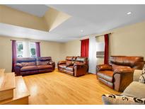 Spacious living room with hardwood floors and comfortable brown leather furniture at 7751 Niagara St, Commerce City, CO 80022
