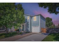Charming two-story home featuring blue siding, a one car garage and mature trees at 1272 Bluebird St, Brighton, CO 80601