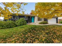 Charming single-Gathering home featuring a striking dark exterior, a bright blue door, and lovely autumn foliage at 2427 S Eldridge Ct, Lakewood, CO 80228