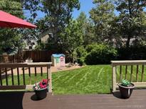 Landscaped backyard featuring a green lawn, wooden deck, and playhouse at 18655 E Garden Pl, Aurora, CO 80015