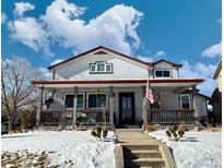 Two-story home with a large front porch and snowy yard at 395 Longspur Dr, Brighton, CO 80601