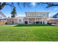 Large grassy backyard with covered patio, brick accents, and mature trees offering shade at 5775 S Pagosa Way, Centennial, CO 80015