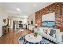 Bright living room featuring a brick wall, light-colored sofa and a view of the modern white kitchen at 2636 W 27Th Ave, Denver, CO 80211