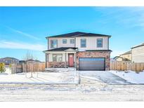 Two-story home with brick and siding exterior, attached garage, and snowy front yard at 13315 Xanthia St, Thornton, CO 80602