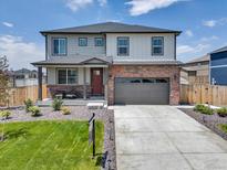 Charming two-story home featuring a brick facade, a well-manicured lawn, and an attached two-car garage at 13315 Xanthia St, Thornton, CO 80602