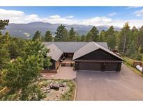 Spacious home with mountain views, a large driveway, and a peaceful koi pond creates inviting curb appeal at 26452 Wolverine Trl, Evergreen, CO 80439