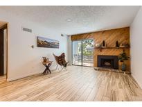 Bright living room featuring wood floors, a brick fireplace, and access to a private balcony at 7665 E Eastman Ave # 111A, Denver, CO 80231