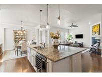 Open-concept kitchen featuring a large island with granite countertops and pendant lighting at 3529 Xanthia Ct, Denver, CO 80238