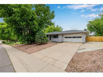 Charming single-story home with a two-car garage and mature trees in a well-maintained front yard at 8231 E Lehigh Dr, Denver, CO 80237