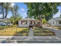 Charming single-story home with a covered porch, mature tree, and fenced front yard at 5240 Dudley St, Arvada, CO 80002