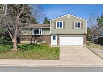 Charming split-level home featuring a two-car garage, brick accents, and a well-maintained front lawn at 9375 W David Ave, Littleton, CO 80128