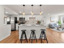 Bright kitchen featuring a center island with barstool seating, stainless steel appliances, and modern white cabinets at 1709 Wabash St, Denver, CO 80220