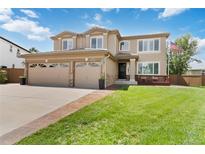 Charming two-story home with a well-manicured lawn, a three-car garage, and a cozy front porch at 9169 Fox Fire Way, Highlands Ranch, CO 80129