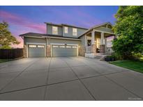 Charming two-story home showcasing a manicured lawn and a spacious three-car garage with stone accents on the facade at 12972 Uinta Ct, Thornton, CO 80602