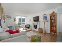 Bright living room featuring hardwood floors, a fireplace, and large windows for natural light at 1050 N Lafayette St # 408, Denver, CO 80218