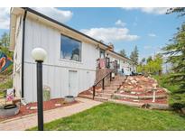 Charming home exterior showcasing a brick stairway, manicured lawn and bright white siding at 11827 Brook Rd, Golden, CO 80403
