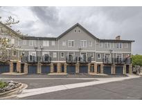 Gray townhouse features private balconies above garages, complemented by brick accents and well-maintained landscaping at 2951 W Riverwalk Cir # N, Littleton, CO 80123