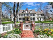 Charming two-story home with a white picket fence, brick pathway, and manicured landscaping at 4682 S Franklin St, Englewood, CO 80113