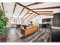 Bright open-concept living area with vaulted ceiling, wood beams, and sleek dark cabinetry at 12674 W 38Th Dr, Wheat Ridge, CO 80033